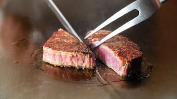A steak being cut with tongs on a grill.