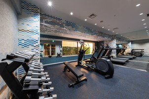 Una palestra con attrezzature per esercizi, una panca e un muro con motivo geometrico.