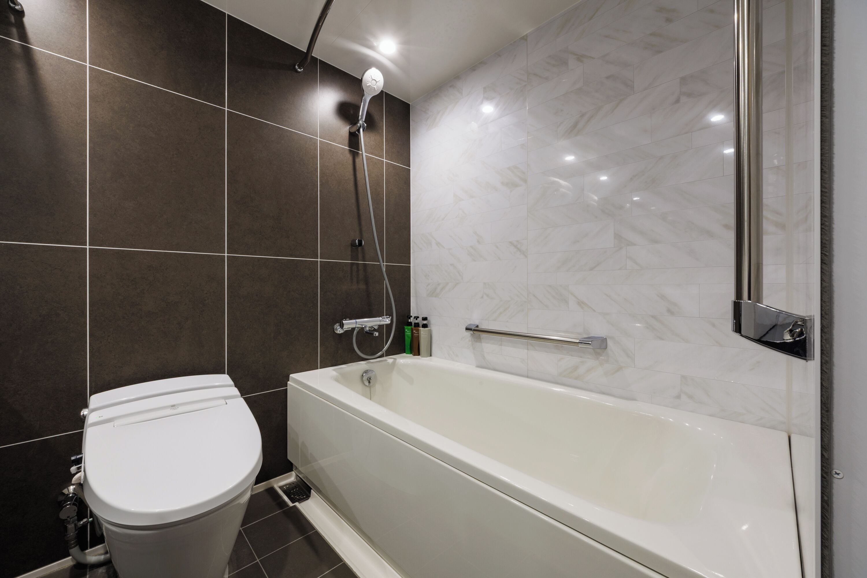 A modern bathroom with a white toilet, a bathtub, and a shower.