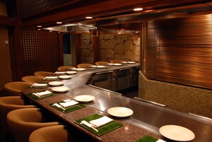 A restaurant with a long counter, multiple chairs, and a stone wall.