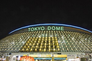 The exterior of Tokyo Dome at night with illuminated signage.