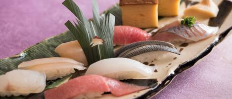 Variedad de sushi sobre un plato de madera con fondo morado.