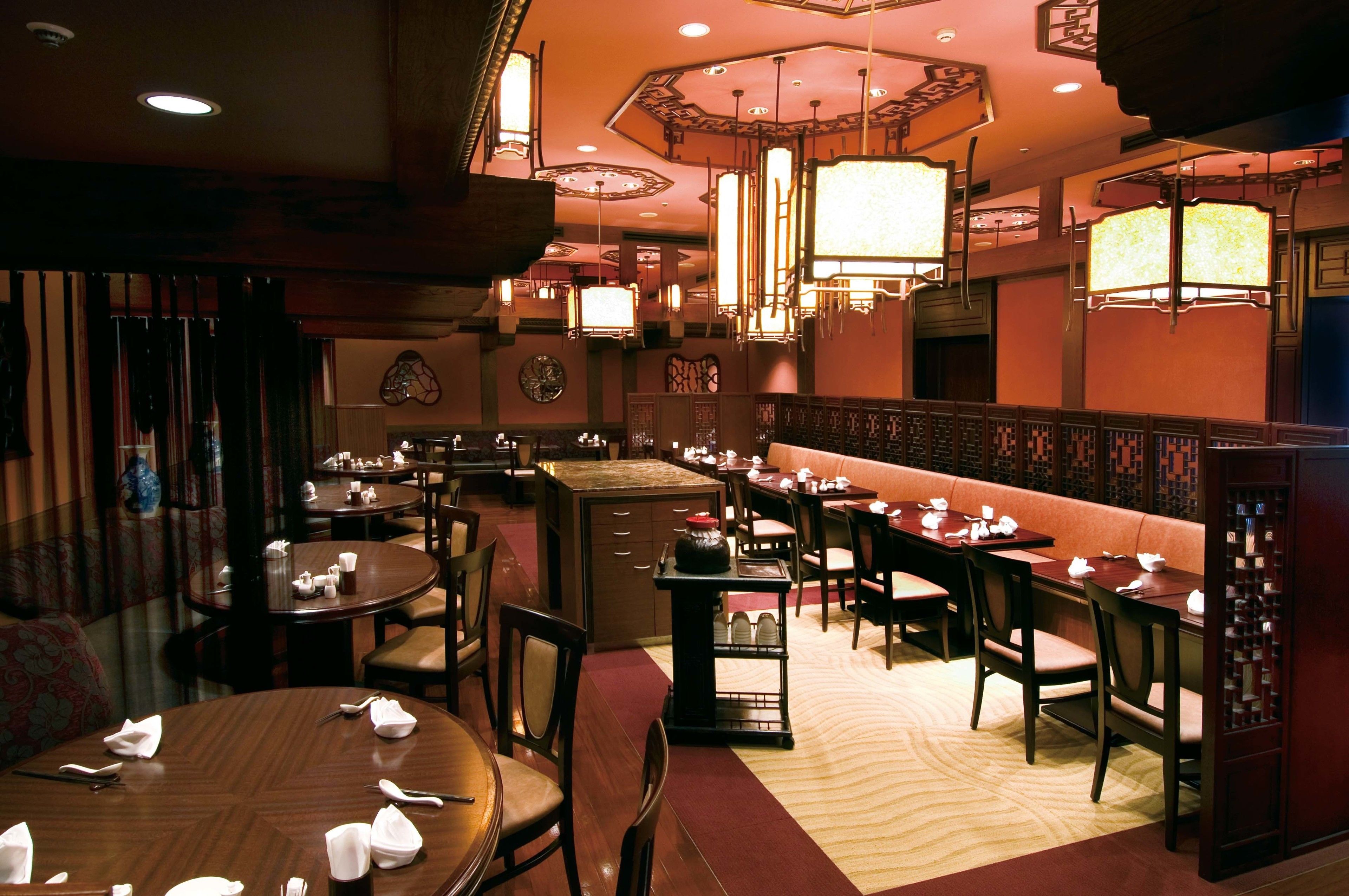 A restaurant with round tables, wooden chairs, and hanging lanterns.