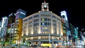 A historic building with a clock tower, surrounded by modern high-rise buildings with illuminated signage. - Hotel Metropolitan Edmont Tokyo (Tokyo)