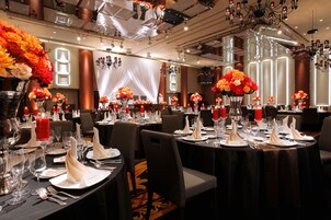 A banquet hall with round tables set for dining, featuring floral centerpieces and red candles.