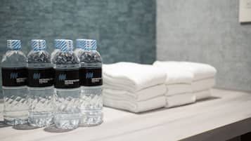 Una encimera de baño con botellas de agua y toallas dobladas con cuidado.