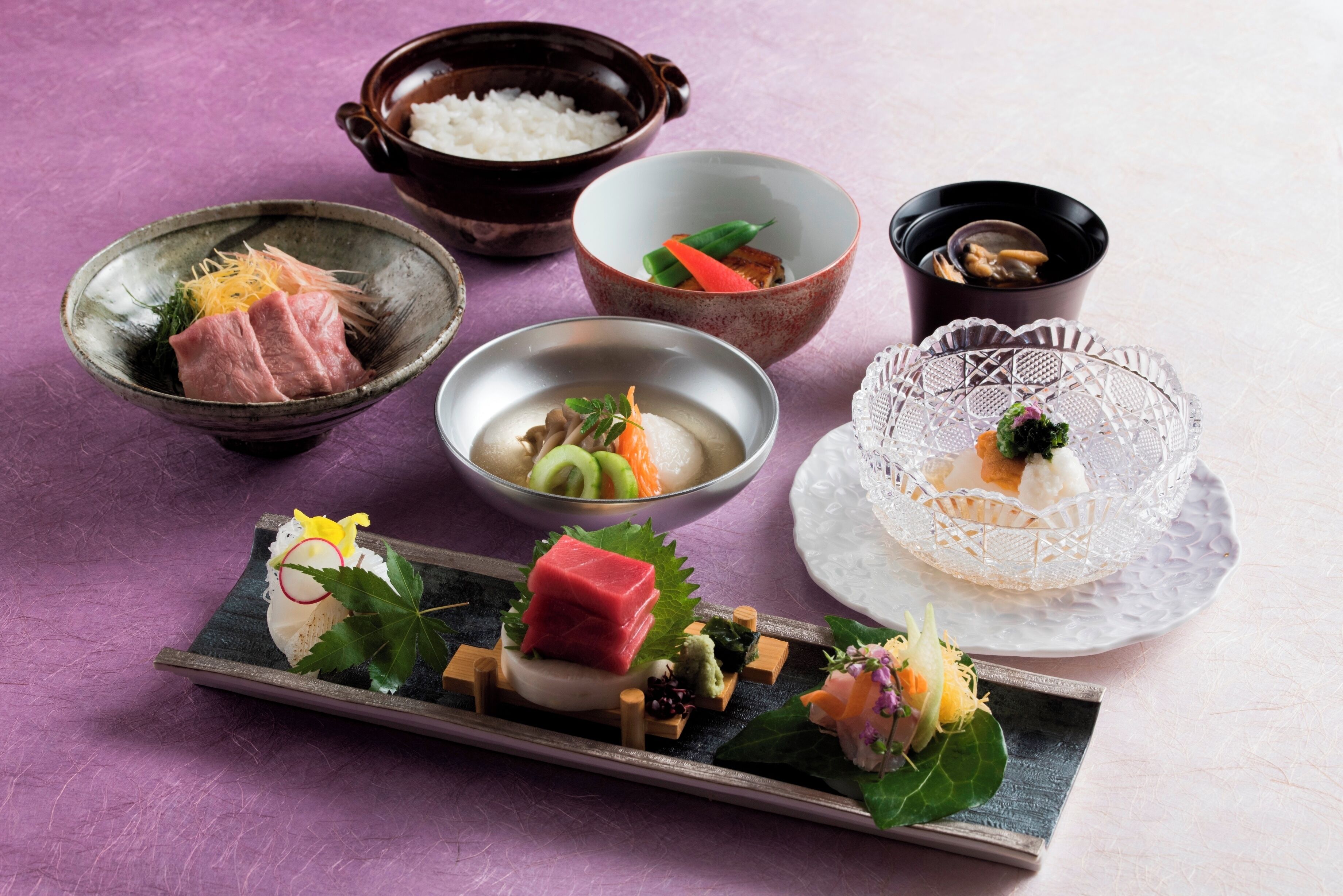 A variety of Japanese dishes arranged on a table, including sashimi, rice, and soup.