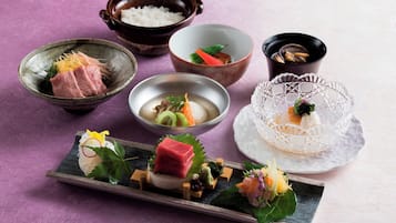 Variedad de platos japoneses sobre una mesa, incluyendo sashimi, arroz y sopa.