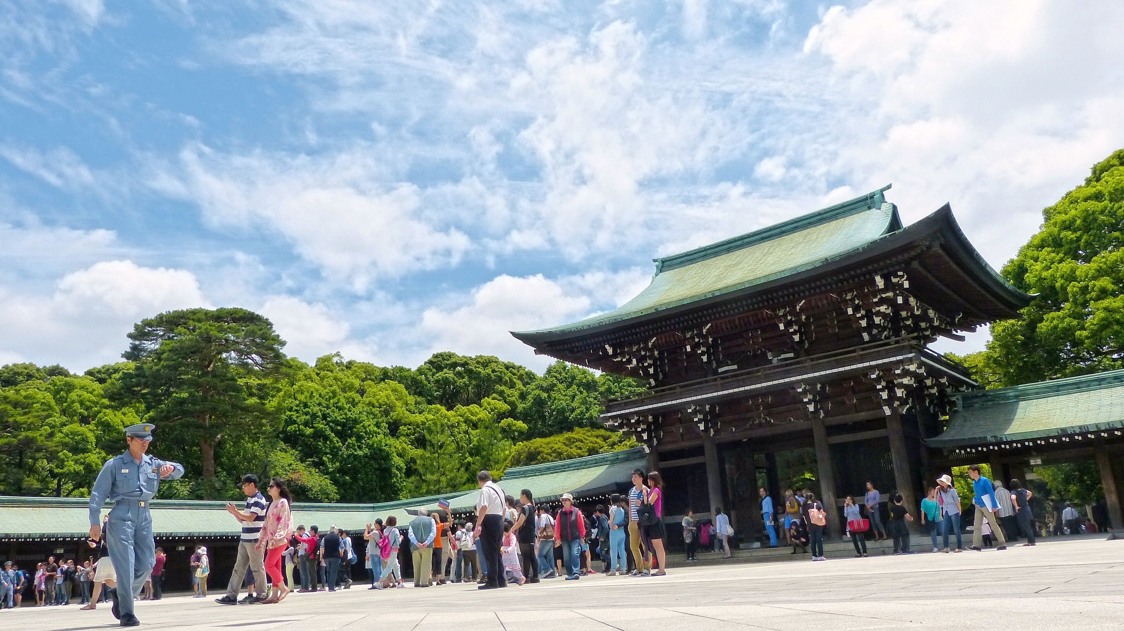 Un edificio japonés tradicional con techo de tejas y estructura de madera, rodeado de gente.