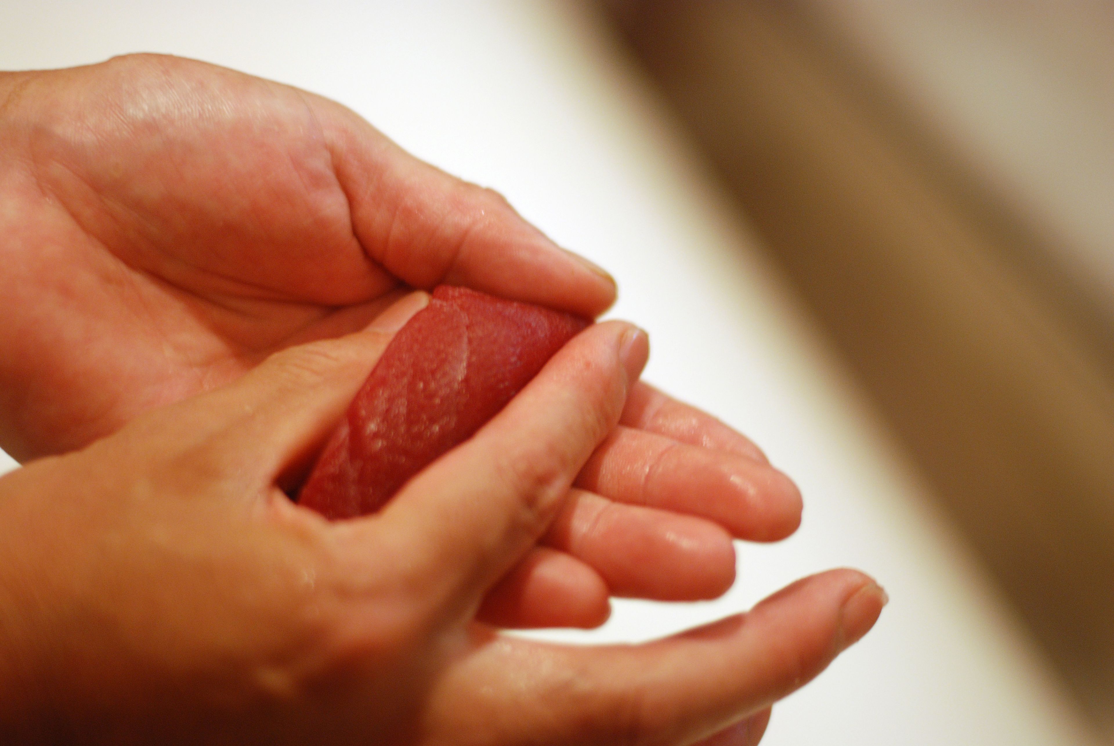 A close-up of hands holding a red object.