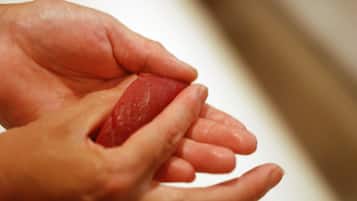 A close-up of hands holding a red object.