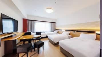 A hotel room with a desk, two beds, a TV, and a window with curtains.