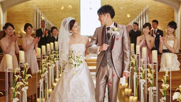 A wedding ceremony in a church with rows of pews and candles.