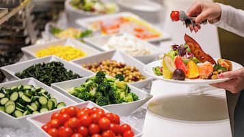 Un bufé con diversos alimentos, entre ellos verduras, frutas y un plato con una variedad de comidas.