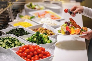 Un bufé con diversos alimentos, entre ellos verduras, frutas y un plato con una variedad de comidas.