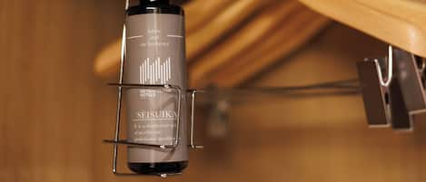 A bottle of Seisuka fabric and air freshener hanging on a metal clip.
