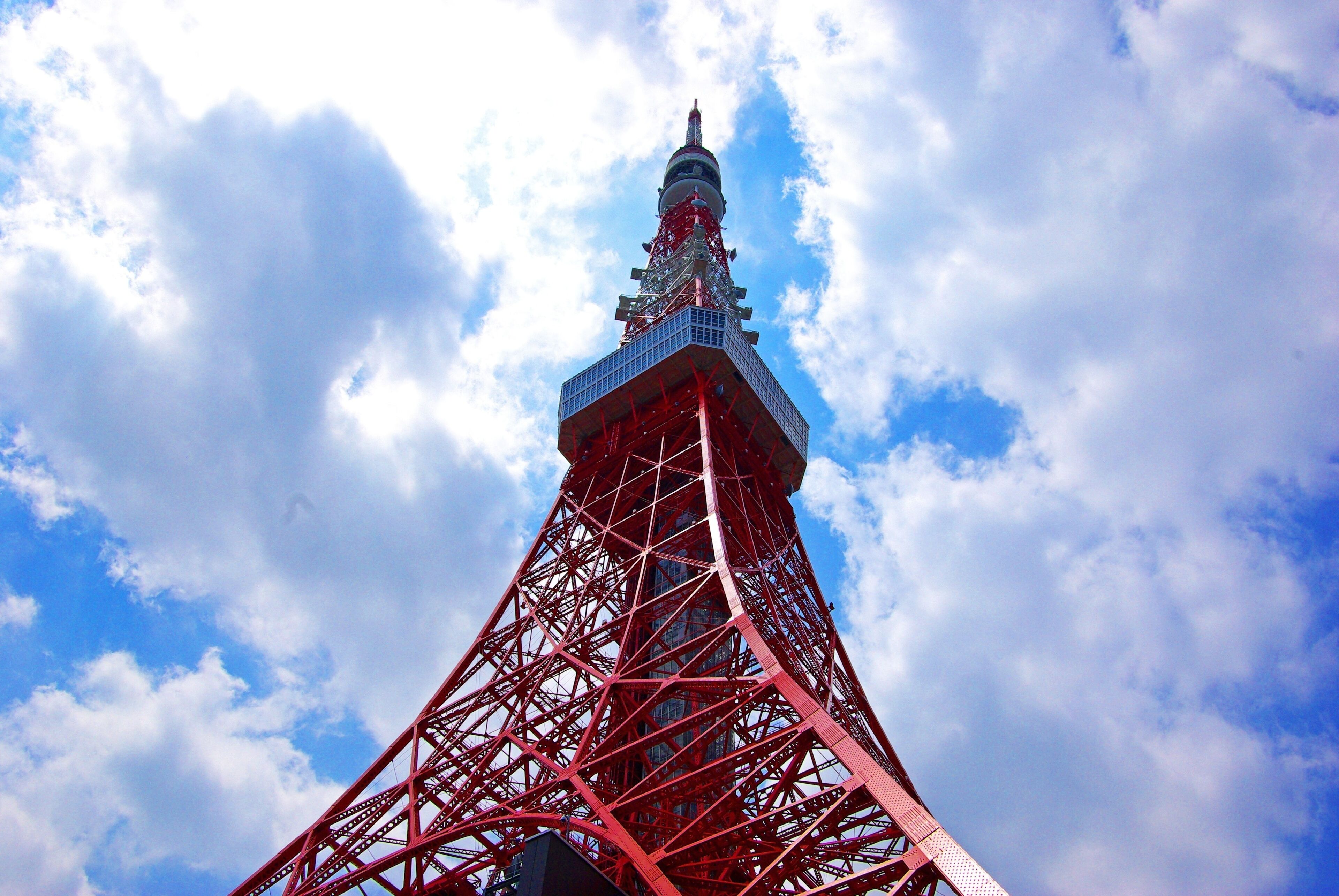 A tall red tower with a complex lattice structure against a partly cloudy sky.