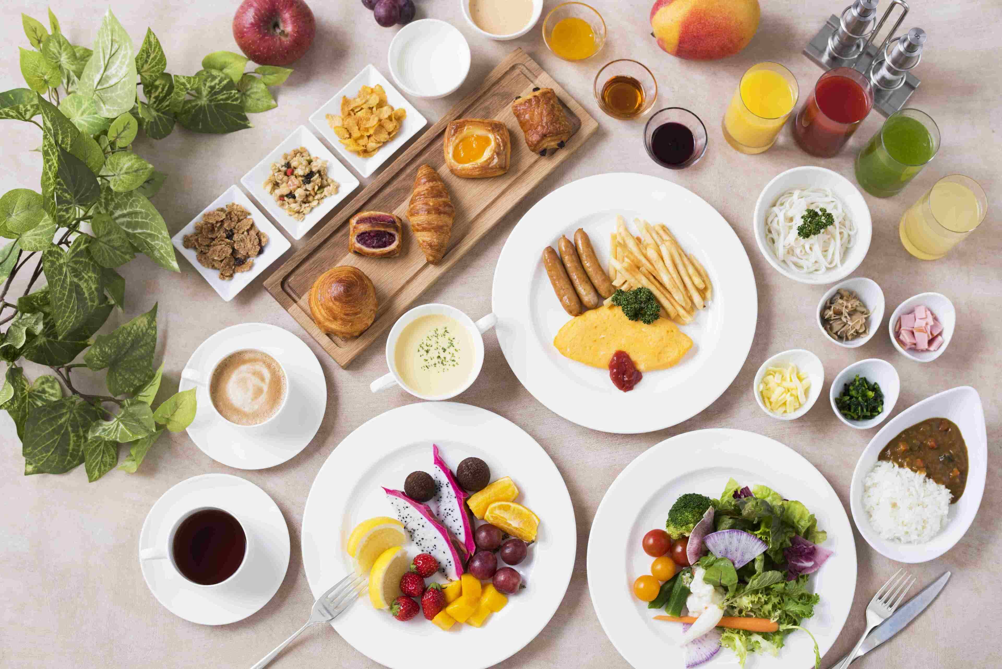 A breakfast spread with various dishes, drinks, and a plant.