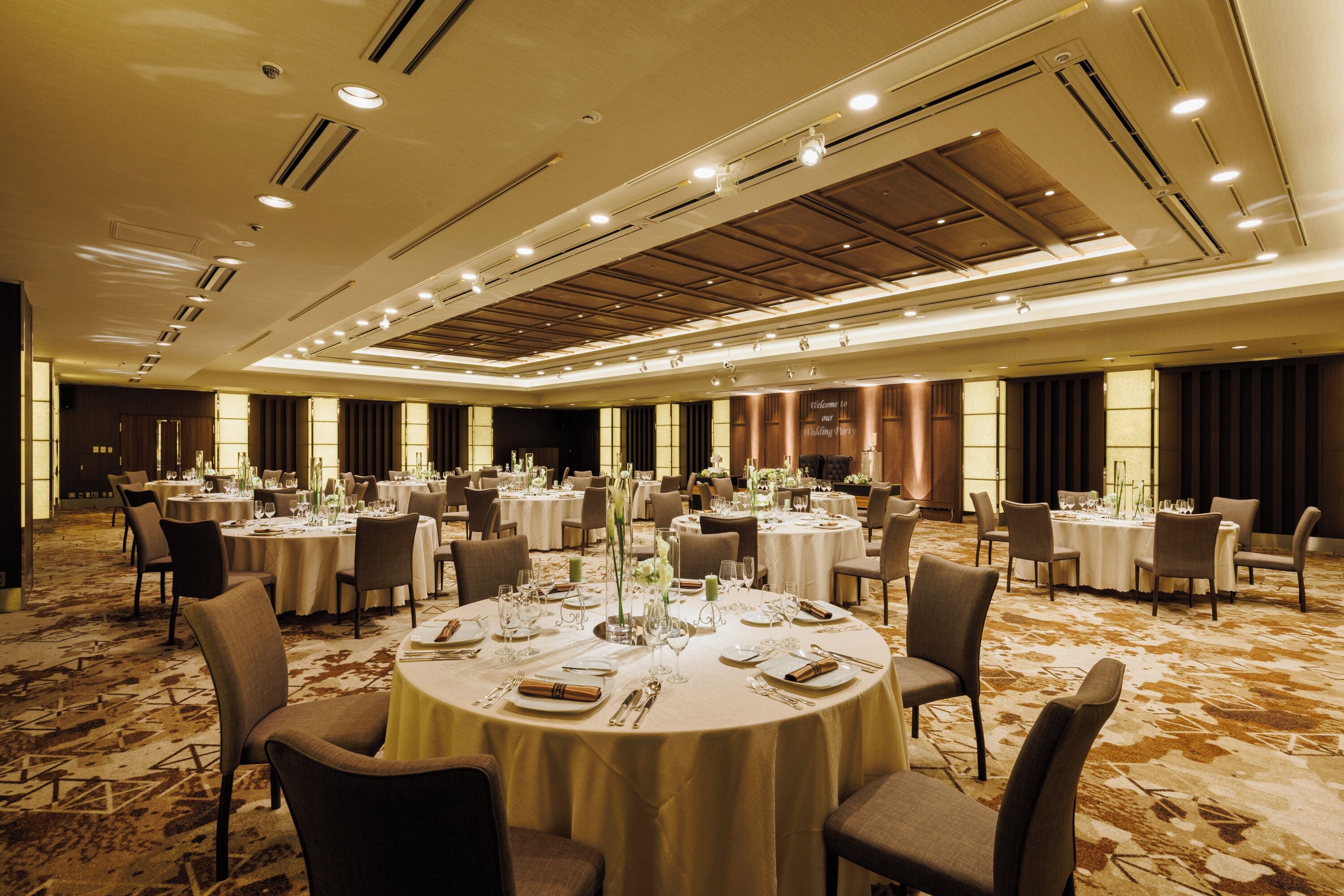 A spacious banquet hall with multiple round tables set for dining, equipped with chairs and table settings.
