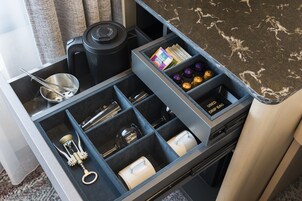 A kitchen drawer with compartments containing a kettle, a coffee maker, a bottle opener, a spice rack, and a drip bag.