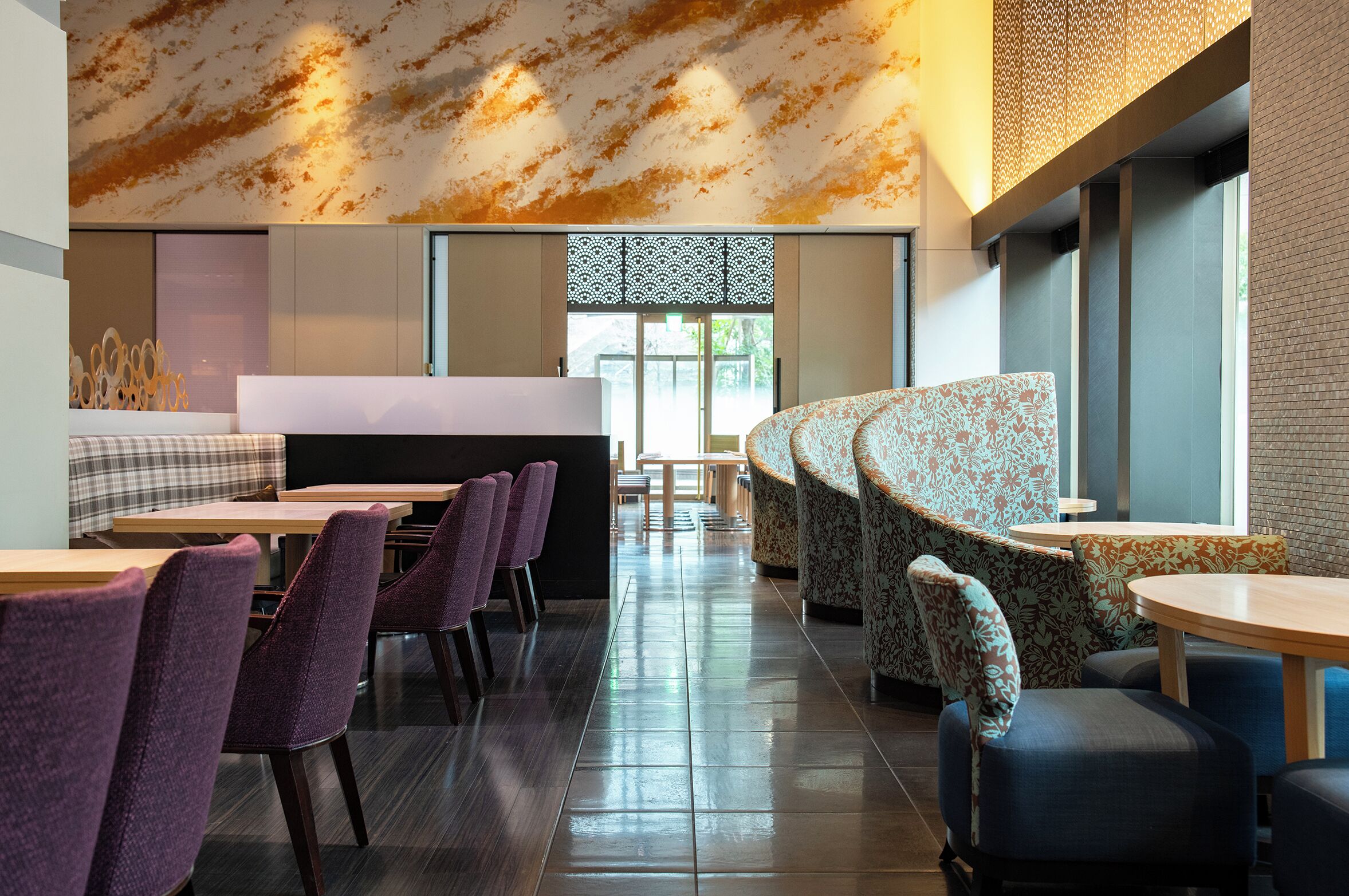 A modern restaurant with a long counter, purple chairs, and a curved seating area.