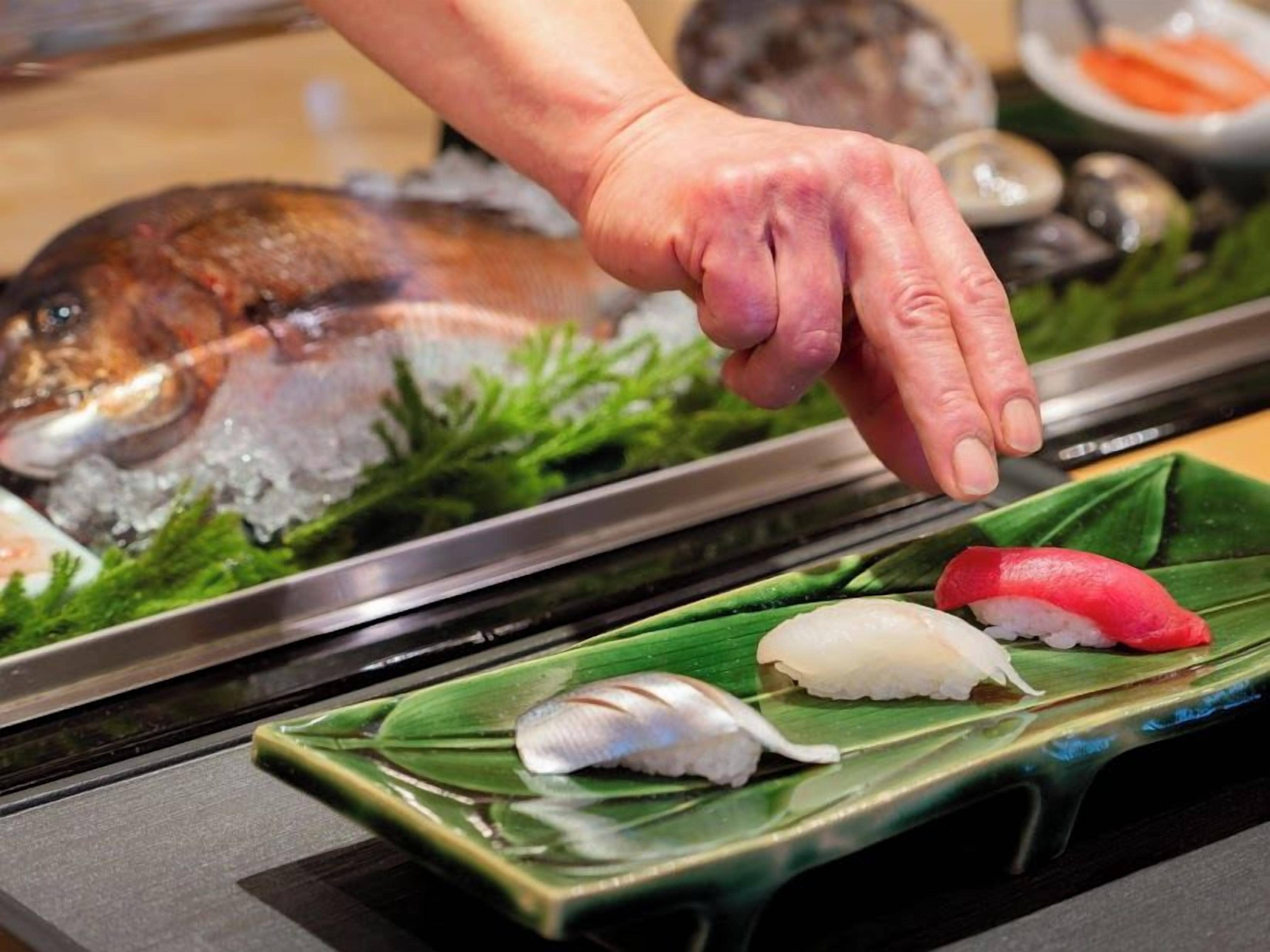 Uma bandeja de sushi com diversos tipos de sushi sobre uma folha verde.