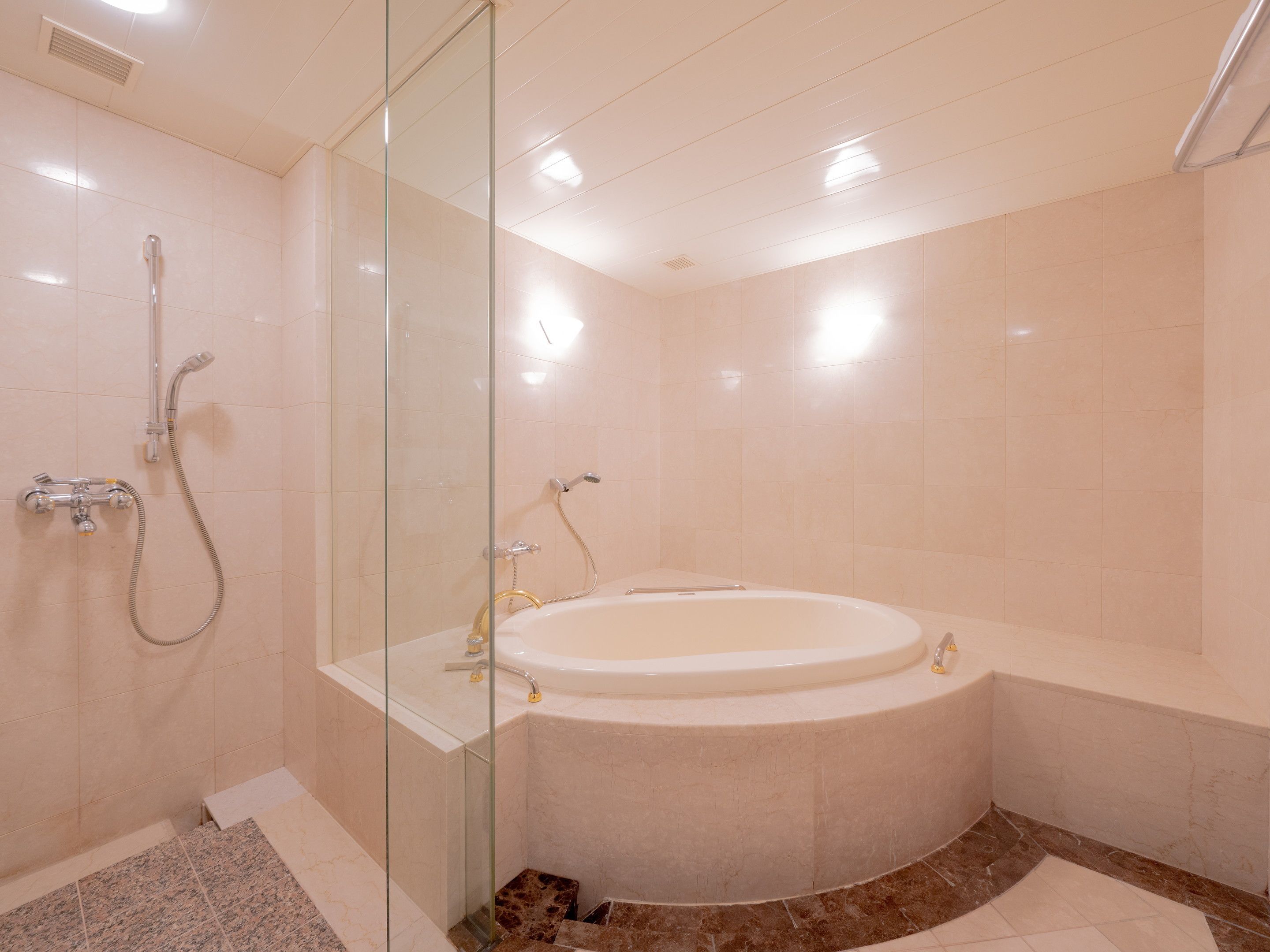 A modern bathroom with a glass-enclosed shower, a freestanding bathtub, and a marble-tiled floor.