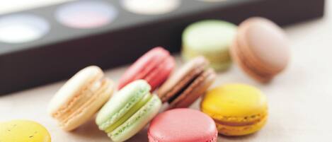 A collection of colorful macarons on a surface with a blurred makeup palette in the background.