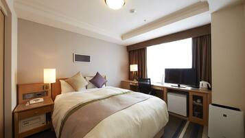 Een hotelkamer met een groot bed, nachtkastjes met lampen, een bureau met computer en een minibar.