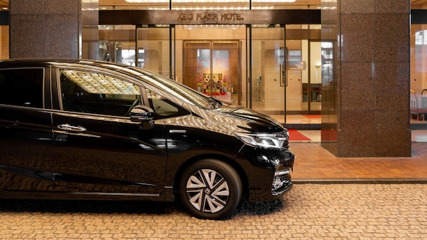 Un coche negro estacionado frente a la entrada del Hotel Keio Plaza.