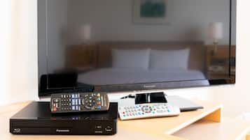 Un lecteur Blu-ray Panasonic DMP-BD90 et une télécommande sont posés sur une table en bois devant un téléviseur.