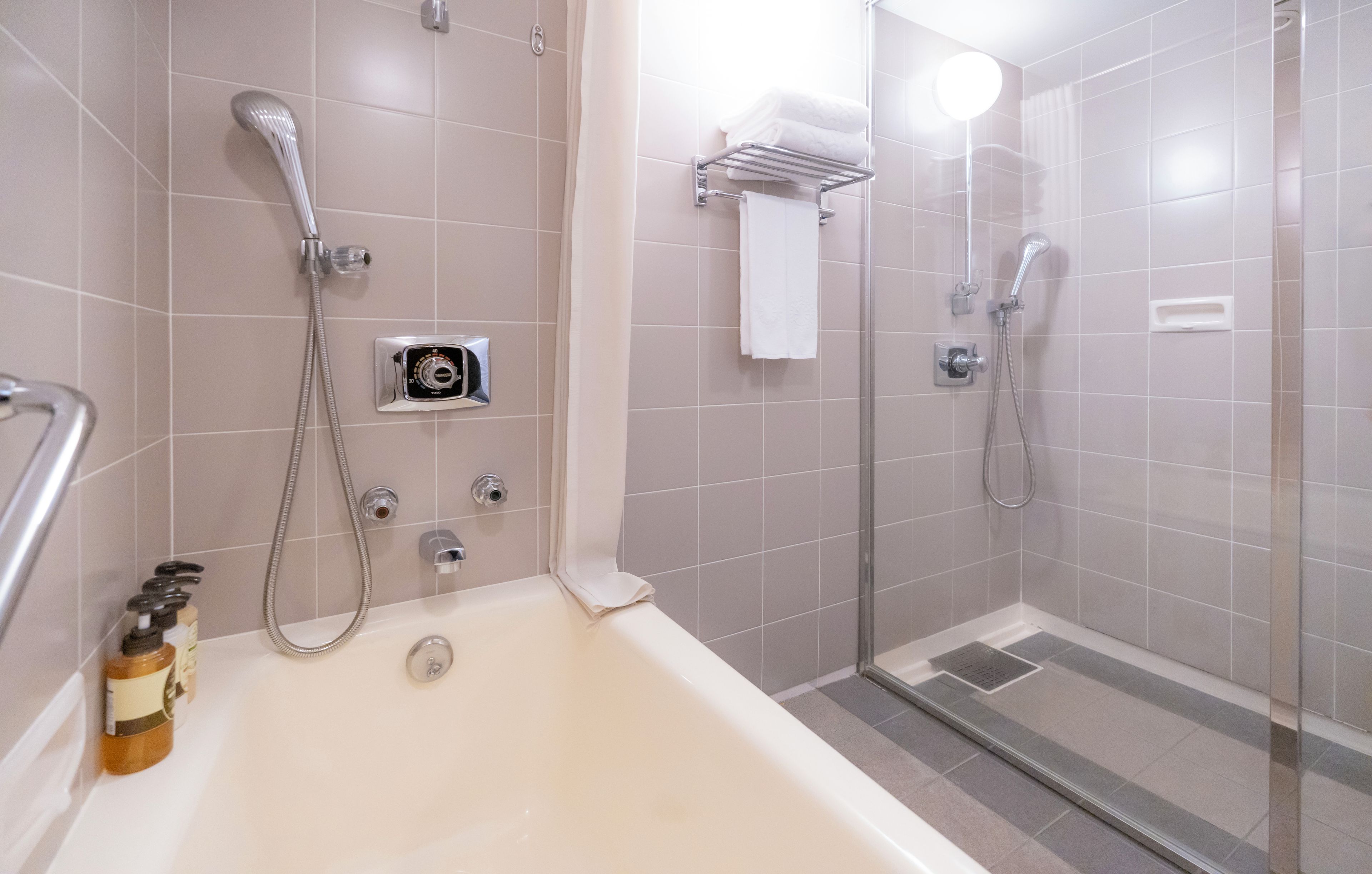 A modern bathroom with a bathtub, a shower with a glass door, and a towel rack.