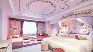 Un dormitorio con temática rosa, con dos camas, un tocador y una zona de estar.