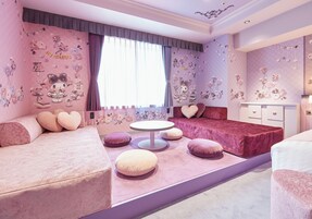 A pink-themed bedroom with a bed, a sofa, a round table, and a dresser.