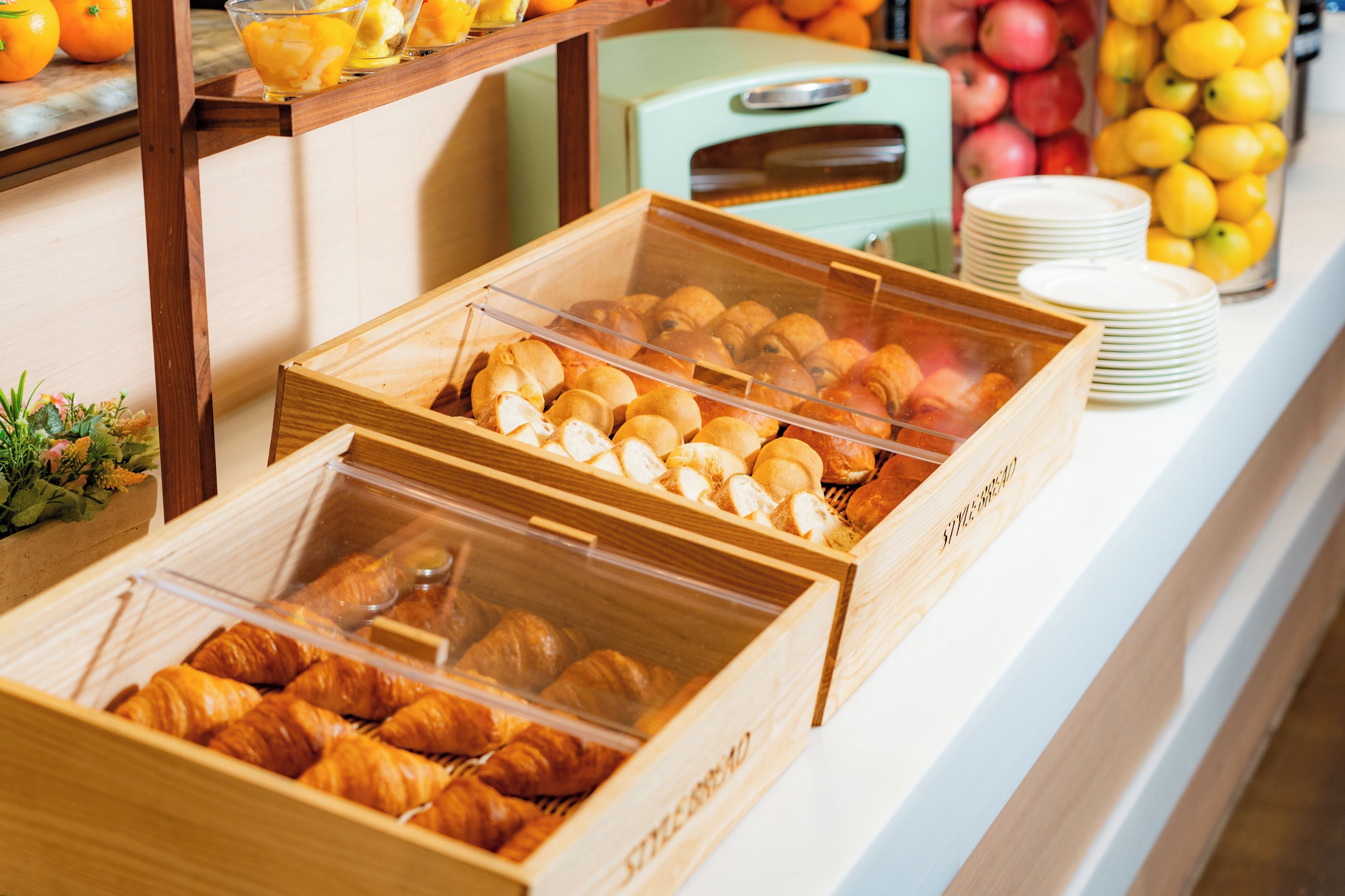 A breakfast buffet with bread, pastries, and fruit.