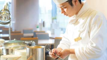 A chef in a white uniform and hat cooking on a stove.