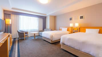 A hotel room with two beds, a desk, a chair, a small table, and a television.