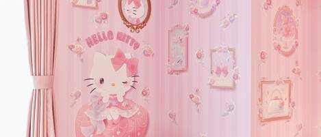 A pink-themed room with a Hello Kitty mural, decorative mirrors, and heart-shaped pillows.