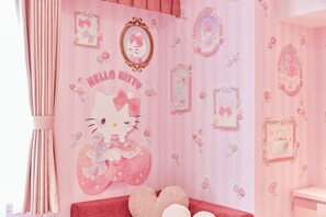 Quarto em tons de rosa com um mural da Hello Kitty, espelhos decorativos e almofadas em formato de coração.