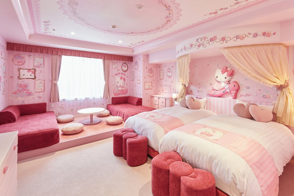 Une chambre à coucher décorée dans des tons roses, avec un grand lit, une petite table et un coin salon.