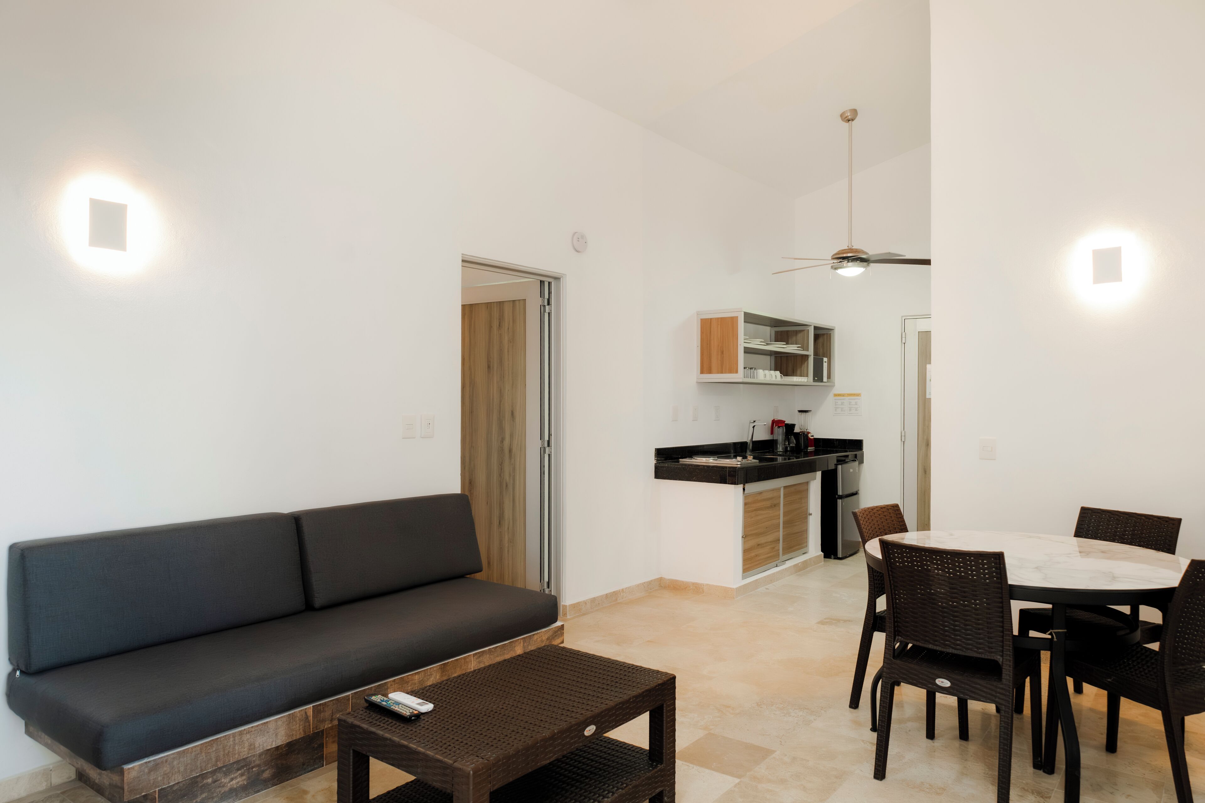 A modern living room with a sofa, a coffee table, and a dining area with a table and chairs.