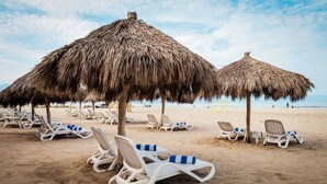 A beach with thatched umbrellas and white lounge chairs. - Villa Varadero (Nuevo Nayarit)