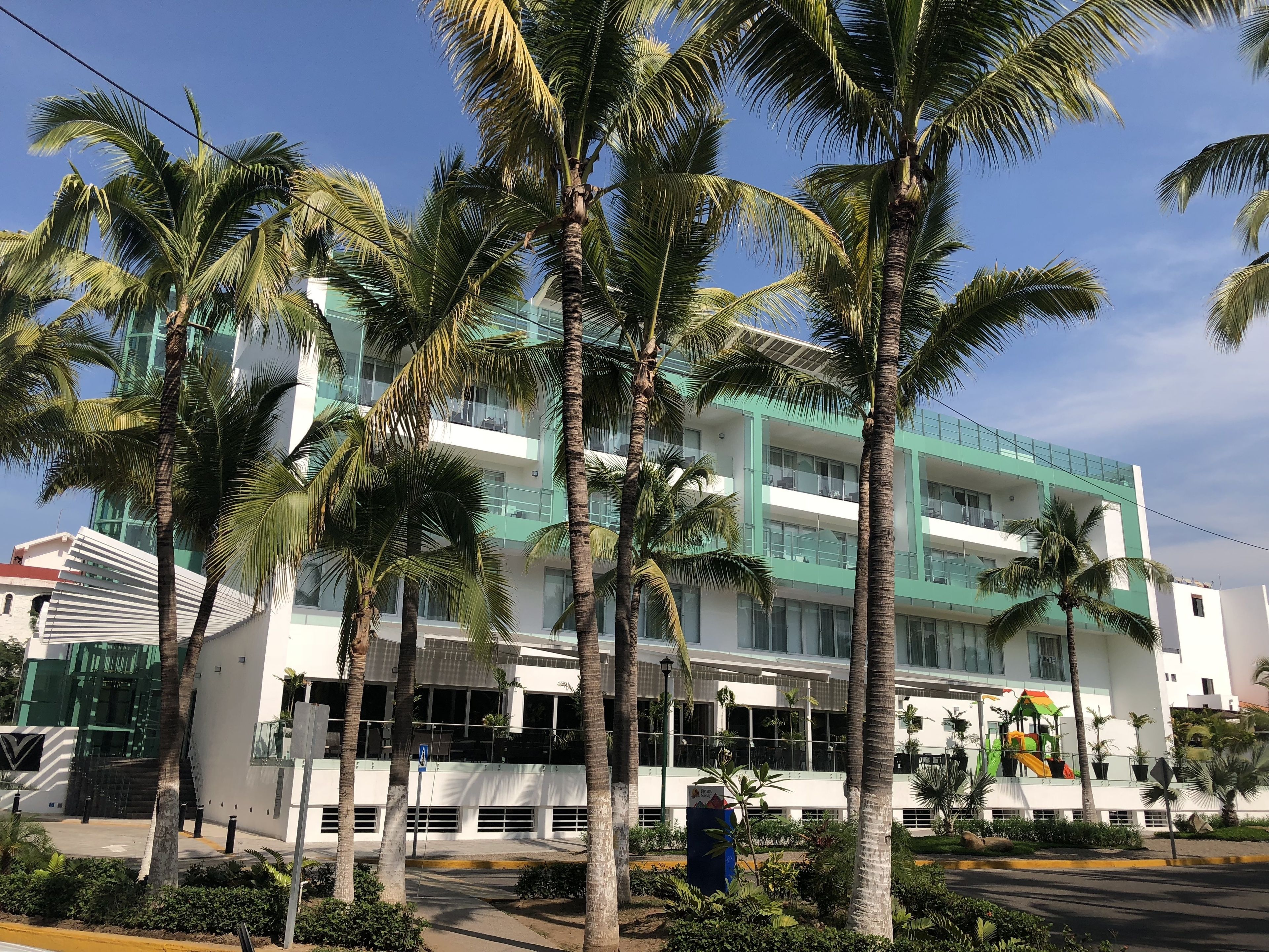 Un edificio moderno de varios pisos, rodeado de palmeras.