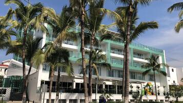 Un edificio moderno de varios pisos, rodeado de palmeras.
