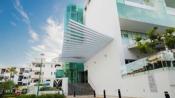 A modern building with a unique slanted roof design, a staircase leading to an entrance, and a sign indicating the building is part of the Torres complex.