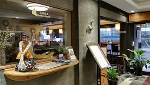A reception desk with a statue, a menu board, and potted plants. - Maritim Hotel (Tønsberg)