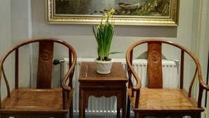 A dining area with two wooden chairs, a small table with a potted plant, and a framed landscape painting on the wall. - Maritim Hotel (Tønsberg)