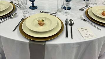 Una mesa redonda dispuesta con platos, cubiertos y una tarjeta de menú.