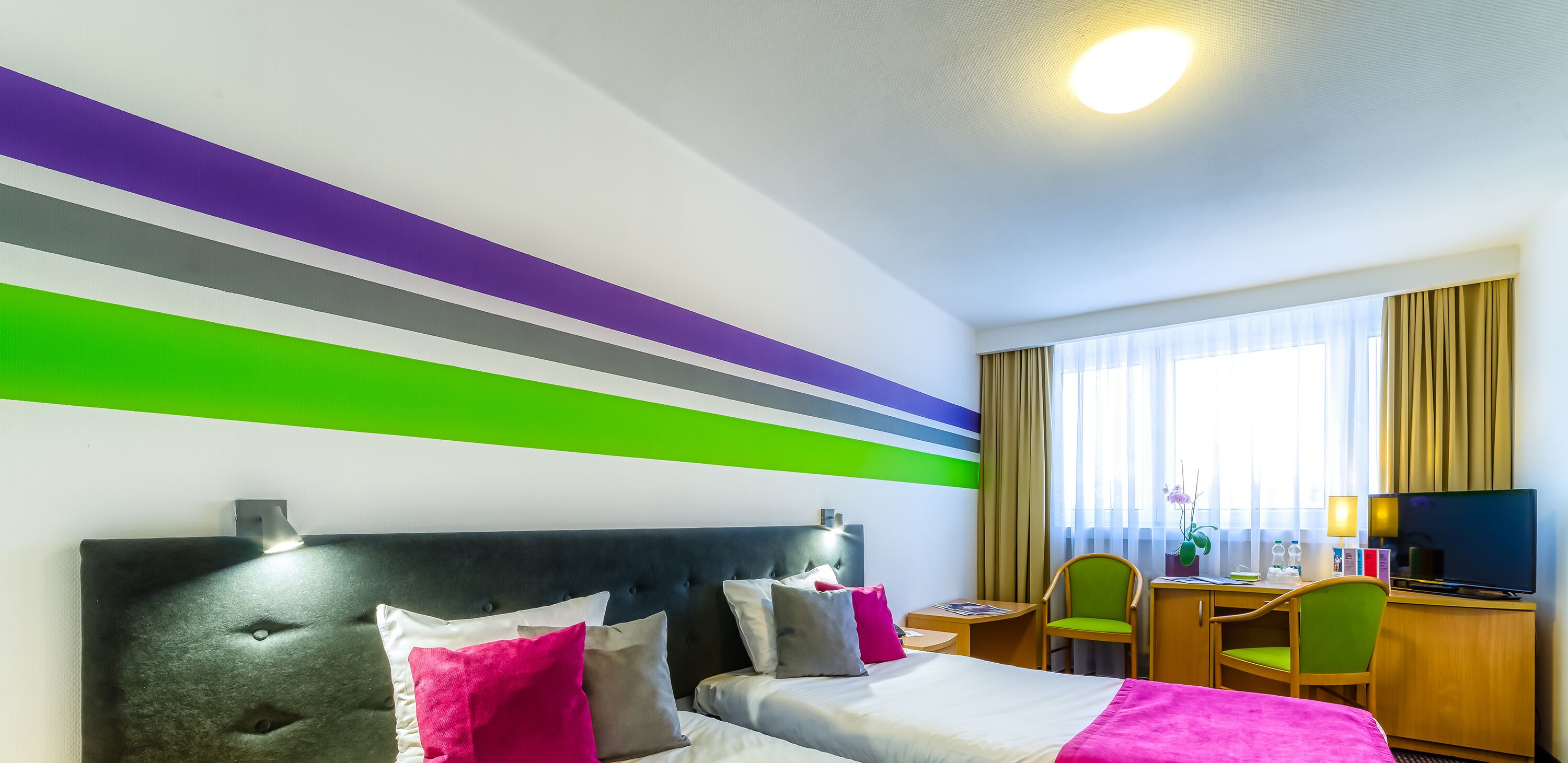 Una habitación de hotel con una cama, un escritorio, una silla y un televisor.