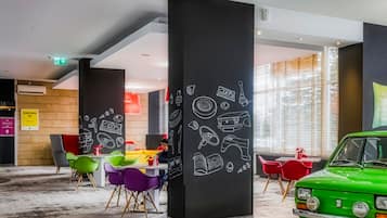 A modern interior with colorful chairs, a vintage car, and wall art depicting various objects.